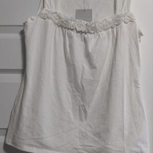 Woman's White sleeveless top. Ruffled flower details around neck. New with tags